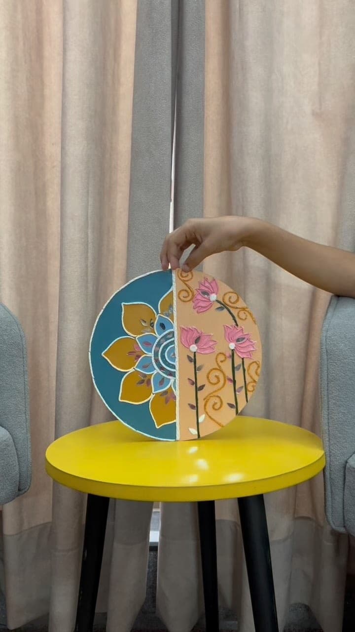 Round artwork that is half mandala in teal and half pink lotus, held up by hand