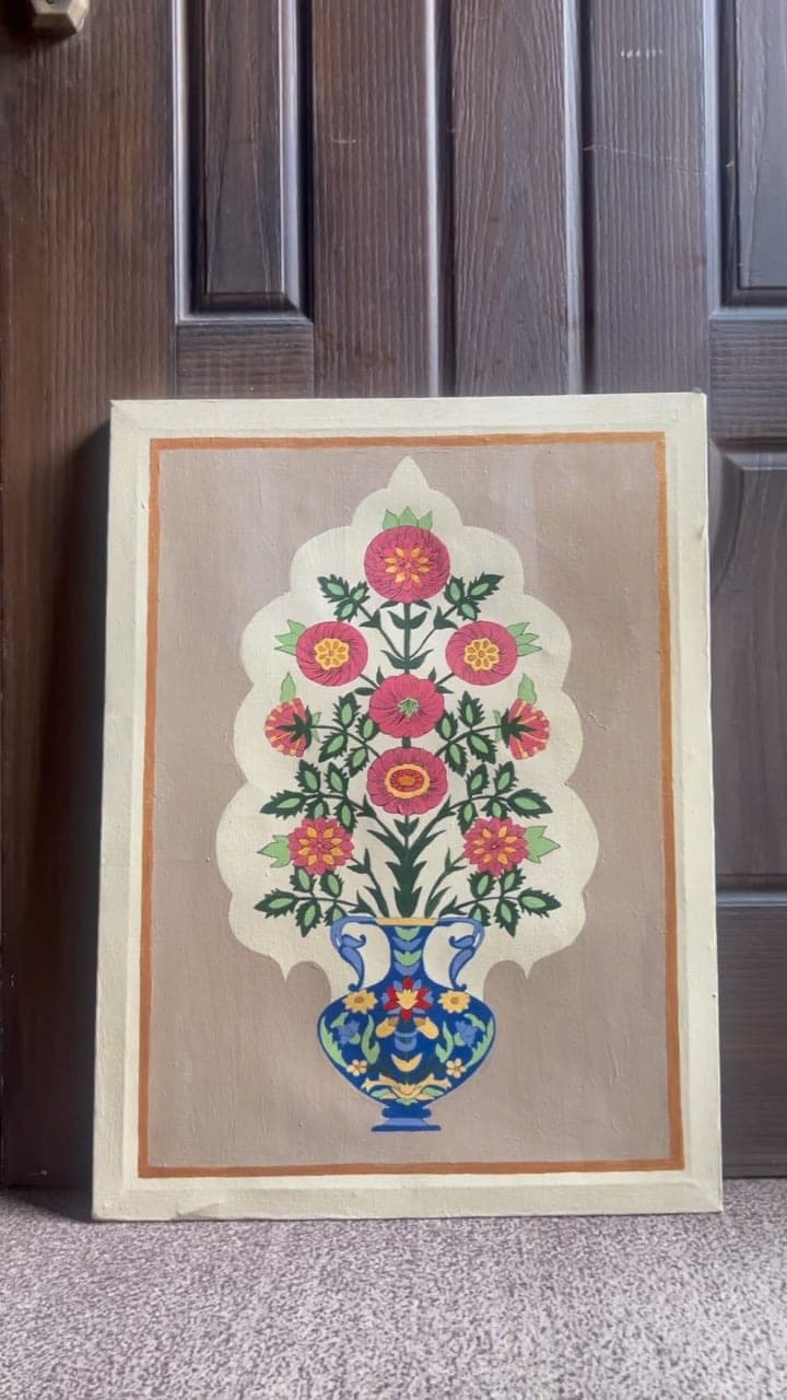 Mughal floral canvas with a gold edge leaning against a wooden door
