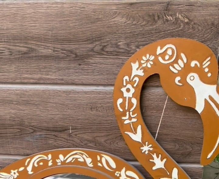 Detail of the Flamingo Mirror: the painted neck and head in burnt orange with white folk motifs