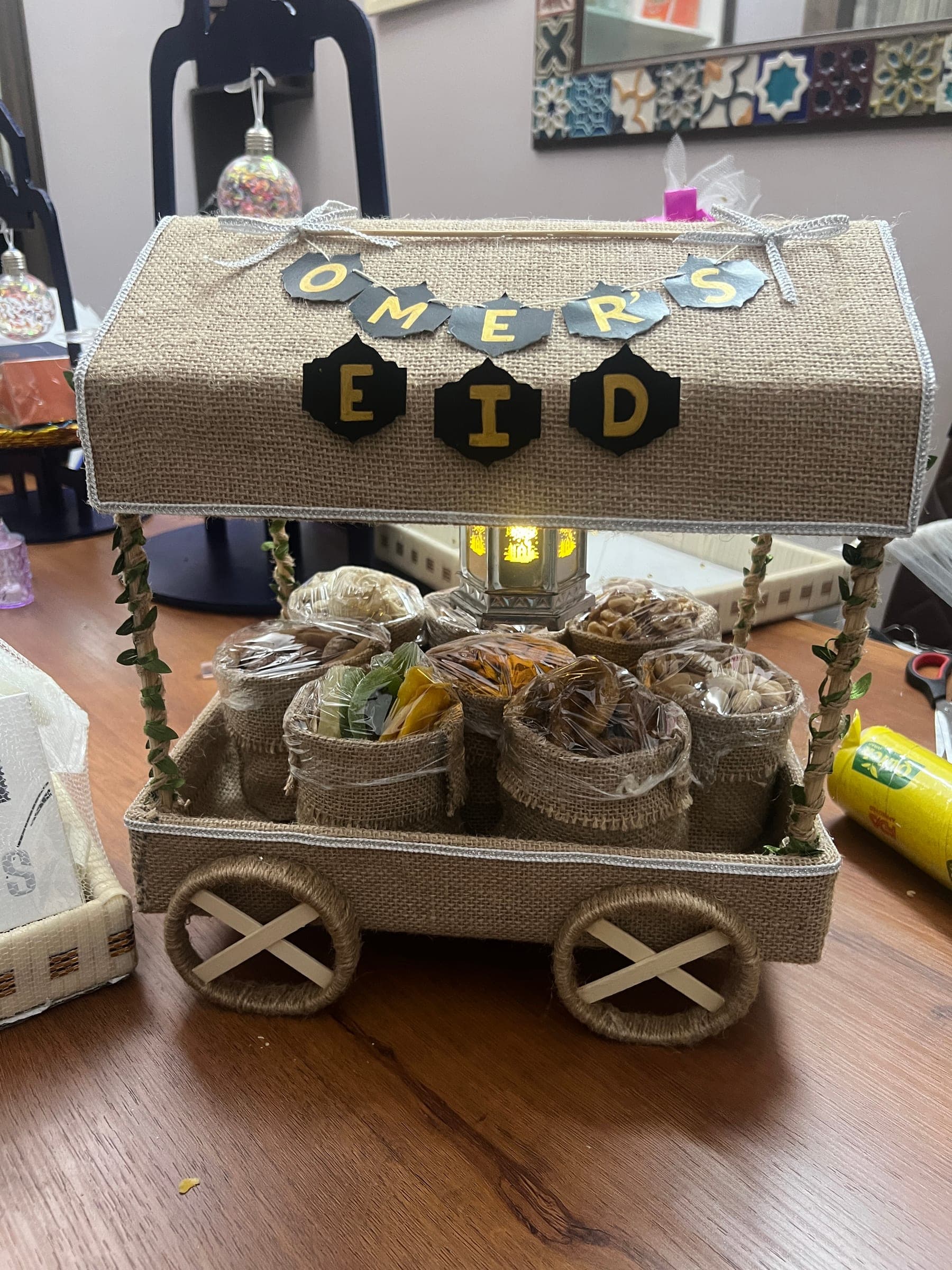 The Eid gift cart from the side, its jute pouches of treats and a small lantern under the canopy