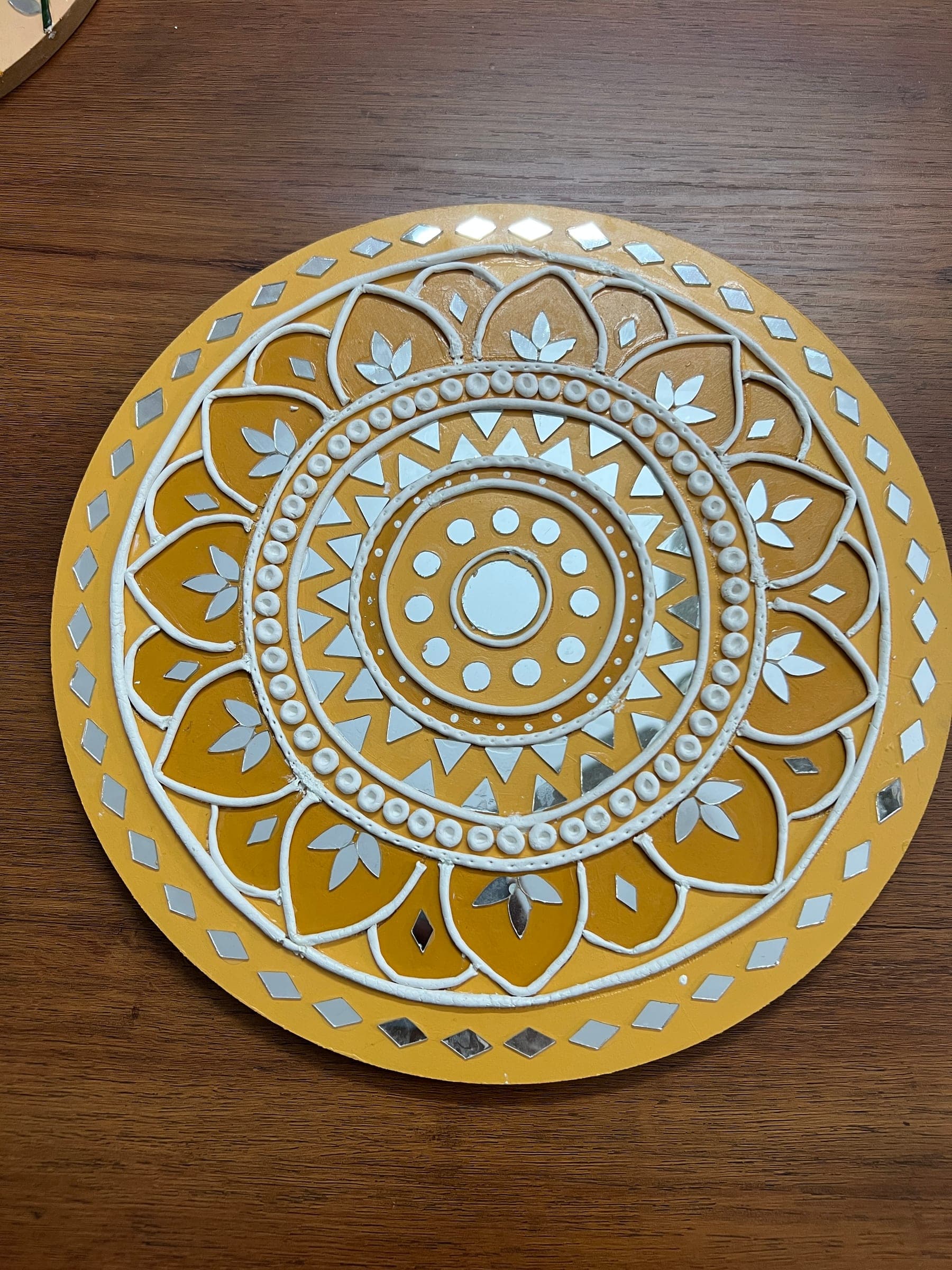 Mustard Lippan mandala with white clay petals, dots and a mirror at its centre