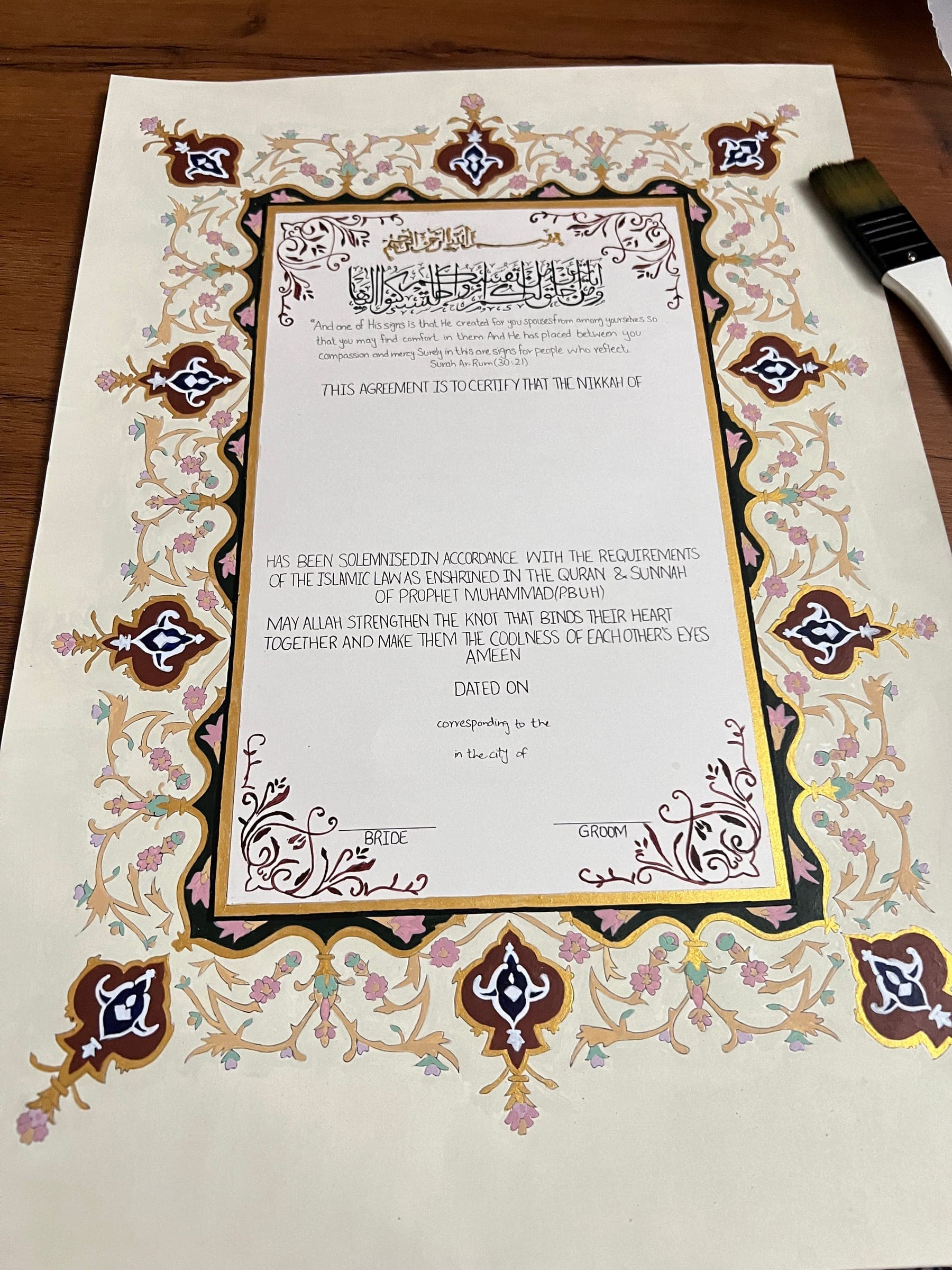 Hand-painted Nikkah Nama on cream paper: a full illuminated border of carnation cartouches, scrolling vines and a gold frame around the certificate text
