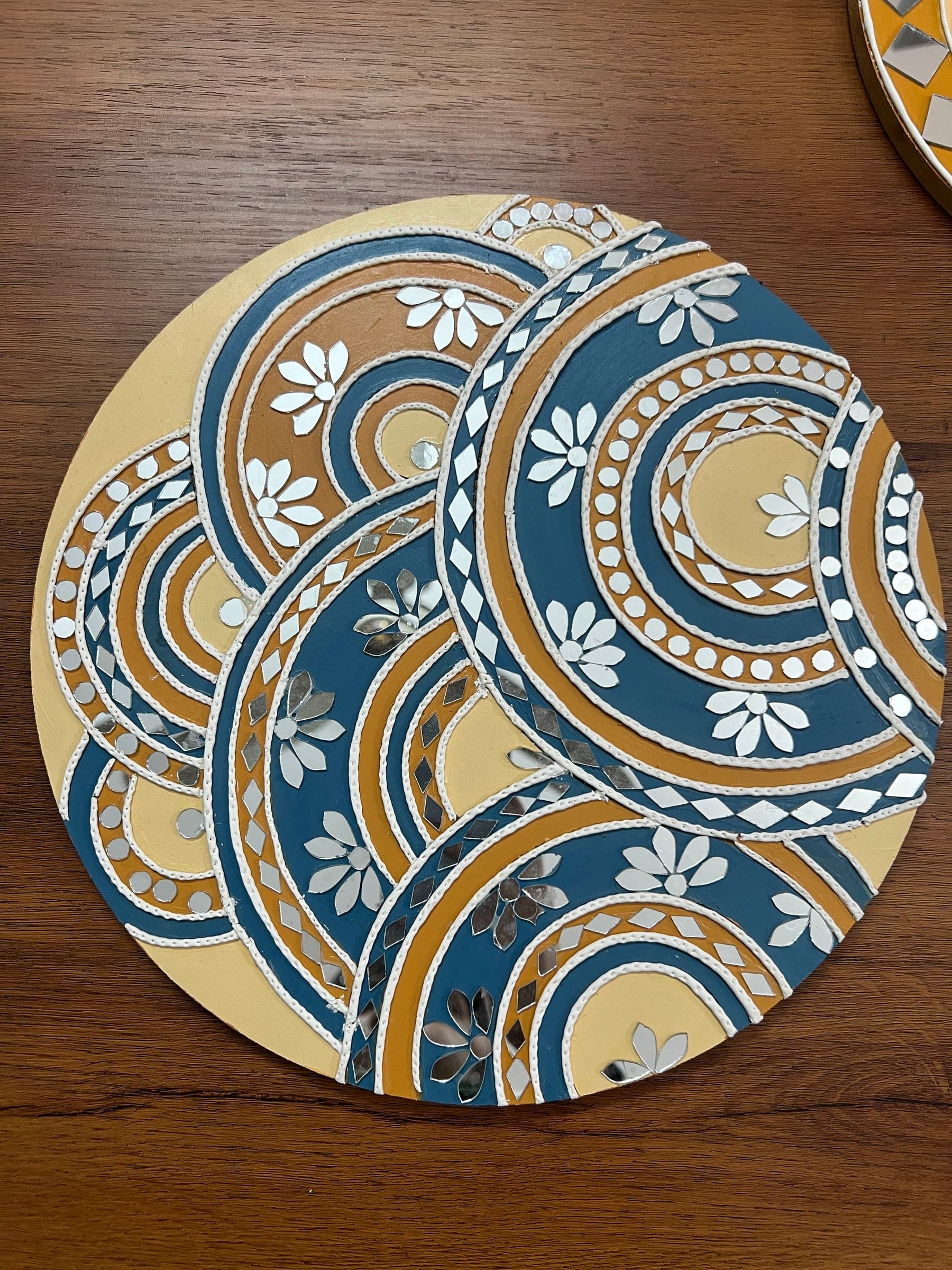 Lippan piece of overlapping circles in blue, mustard and cream, edged with clay dots and small mirrors