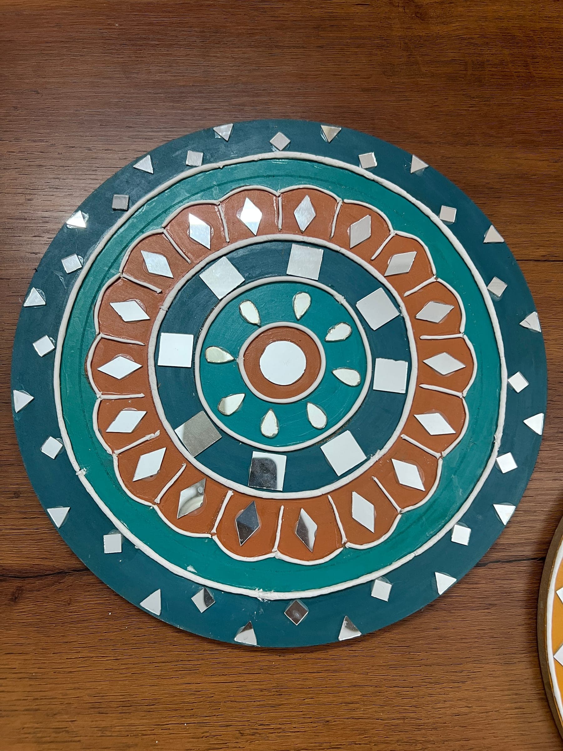 Round Lippan mandala in teal and terracotta with inlaid mirror pieces in concentric rings
