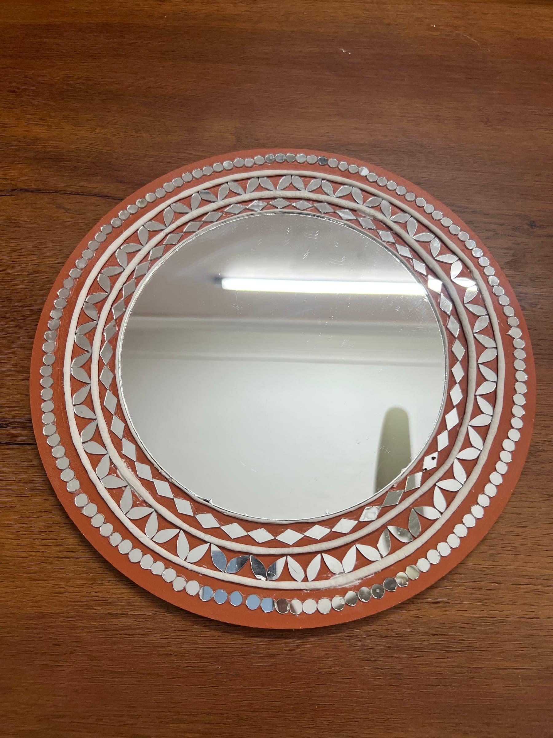 Terracotta Lippan mirror: a round mirror inside rings of white clay pattern and mirror pieces